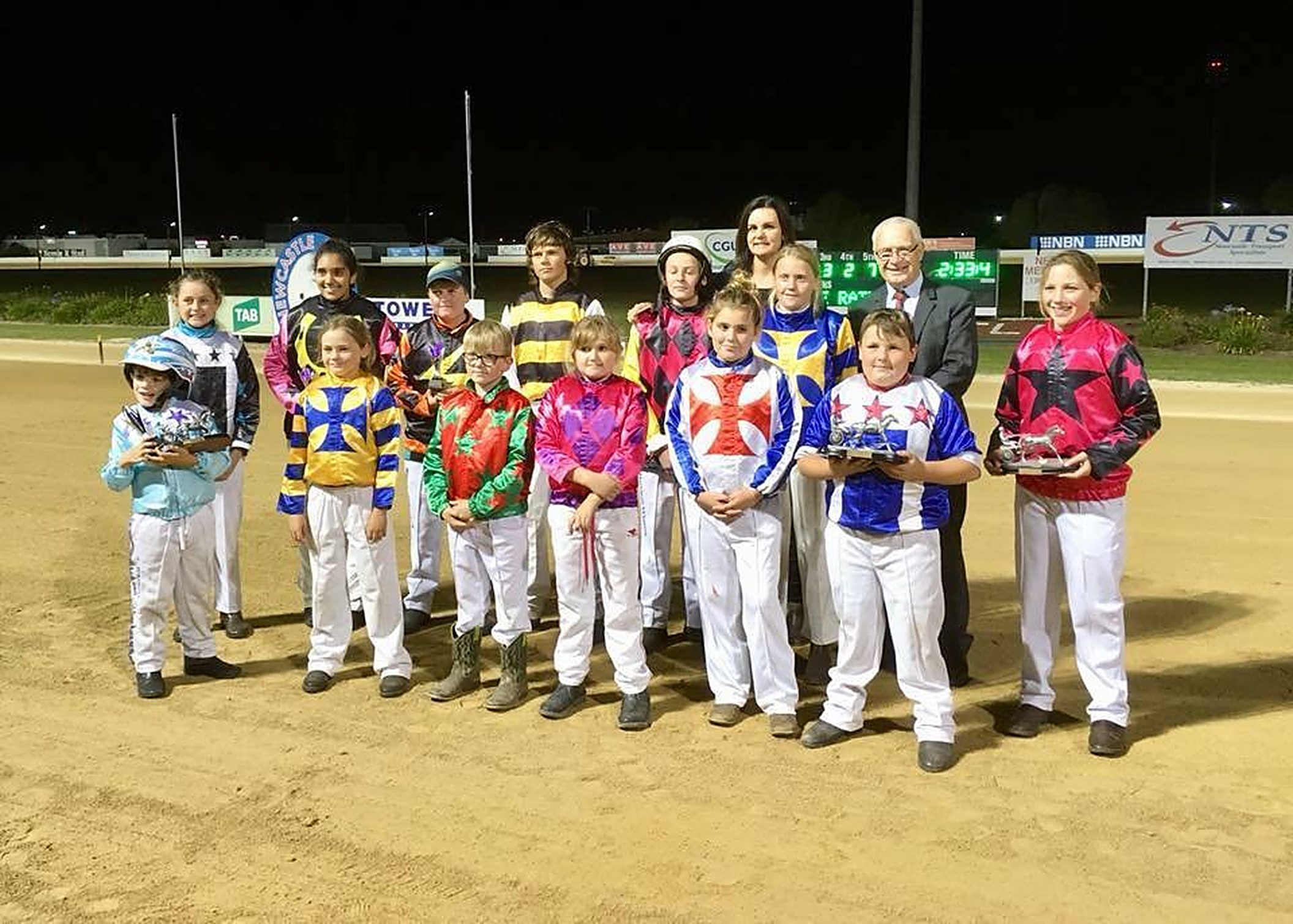 Club drivers in their racing silks lined up on the track at Newcastle Paceway after a race night